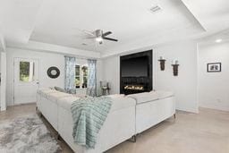 living room featuring ceiling fan and a raised ceiling