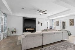 living room featuring a raised ceiling and ceiling fan