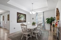 dining space featuring a tray ceiling and a notable chandelier