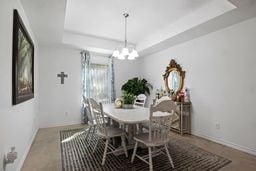 dining room with a raised ceiling and a chandelier