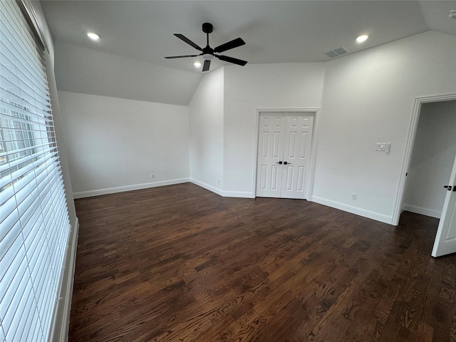 spare room with dark hardwood / wood-style flooring, vaulted ceiling, and ceiling fan