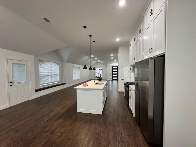 kitchen featuring stainless steel refrigerator with ice dispenser, white cabinetry, decorative light fixtures, and a center island with sink