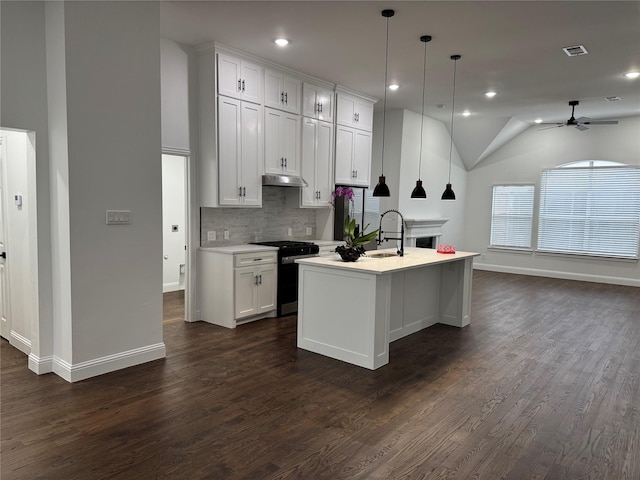 kitchen with hanging light fixtures, gas range, an island with sink, and white cabinetry