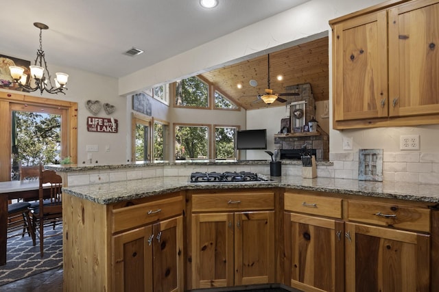 kitchen with ceiling fan with notable chandelier, light stone countertops, stainless steel gas cooktop, and tasteful backsplash