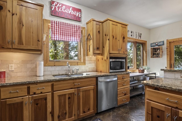 kitchen featuring stone countertops, backsplash, stainless steel appliances, and sink