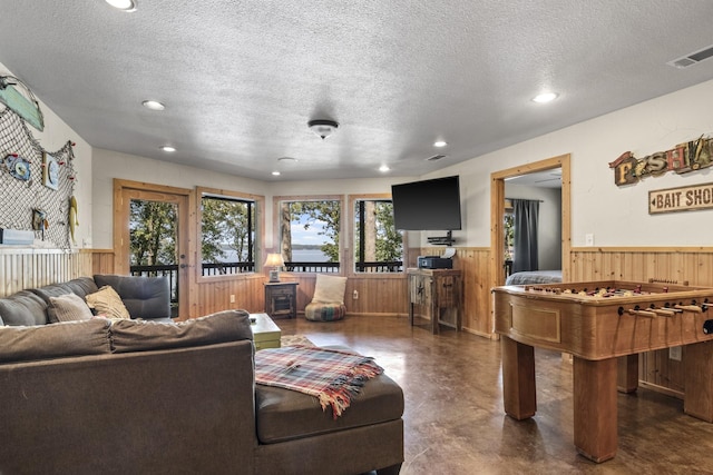 living room featuring a textured ceiling, a wood stove, and wooden walls