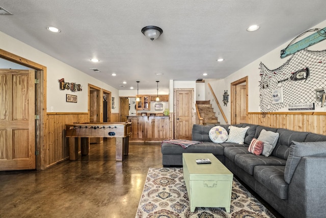 living room featuring a textured ceiling and wooden walls