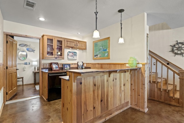 kitchen featuring wood walls, hanging light fixtures, black dishwasher, kitchen peninsula, and a breakfast bar area