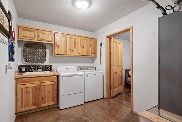 washroom with cabinets, a textured ceiling, washing machine and dryer, and sink