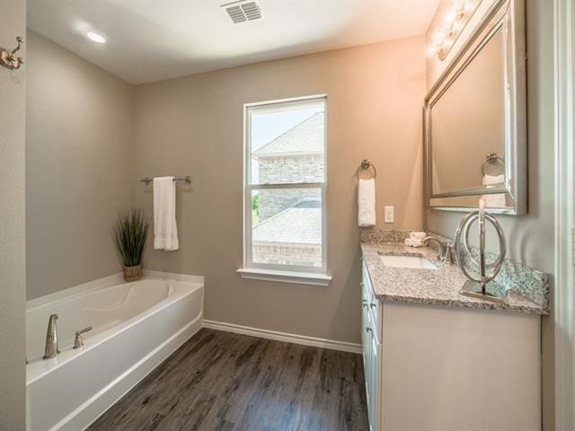 bathroom featuring vanity, hardwood / wood-style flooring, plenty of natural light, and a tub