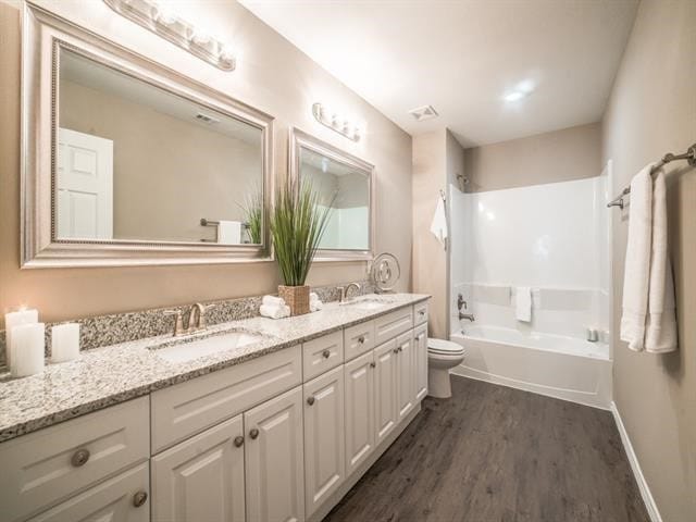 full bathroom with shower / bathing tub combination, hardwood / wood-style floors, vanity, and toilet