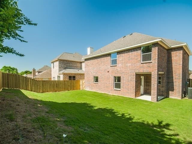 rear view of house featuring a lawn and central air condition unit