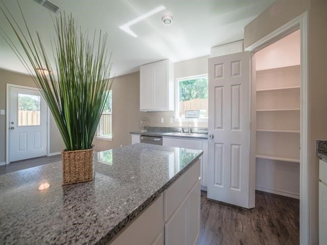 kitchen with light stone counters, a wealth of natural light, dishwasher, dark hardwood / wood-style floors, and white cabinetry