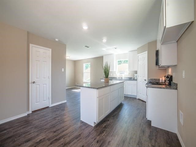 kitchen featuring white cabinets, range, a kitchen island, and dark wood-type flooring