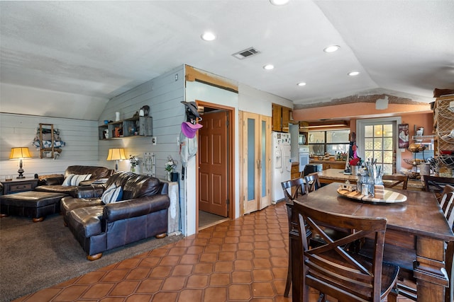 dining space with wood walls and lofted ceiling