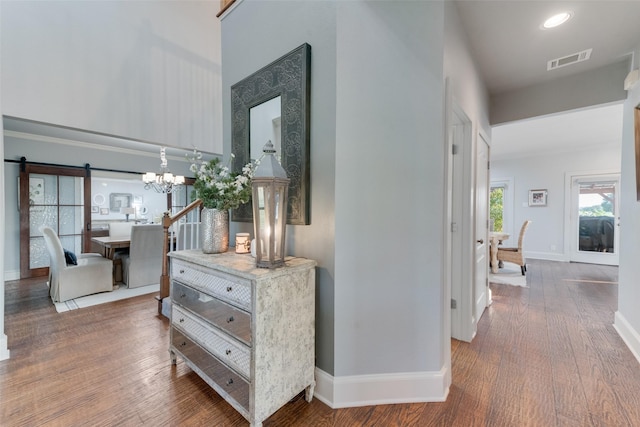 corridor featuring a notable chandelier, a barn door, and dark wood-type flooring