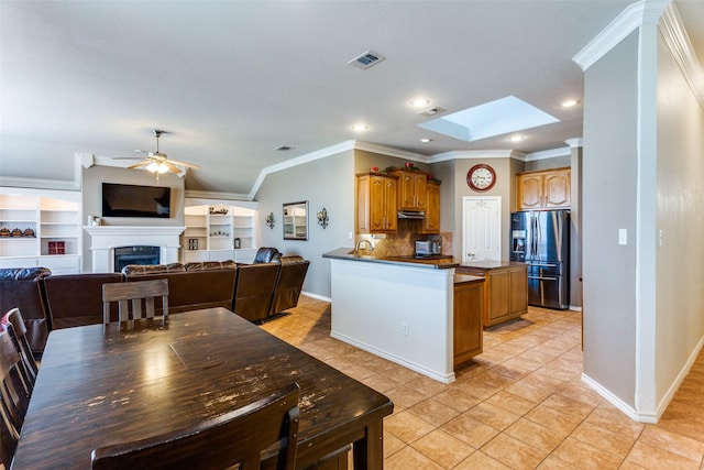 kitchen with backsplash, stainless steel refrigerator with ice dispenser, ceiling fan, light tile patterned flooring, and kitchen peninsula