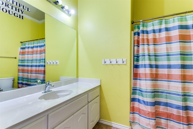 bathroom featuring toilet, vanity, and ornamental molding