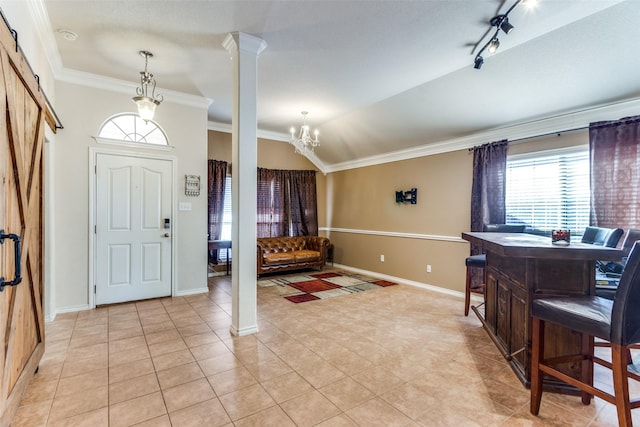 tiled foyer featuring ornate columns, a barn door, a chandelier, lofted ceiling, and ornamental molding