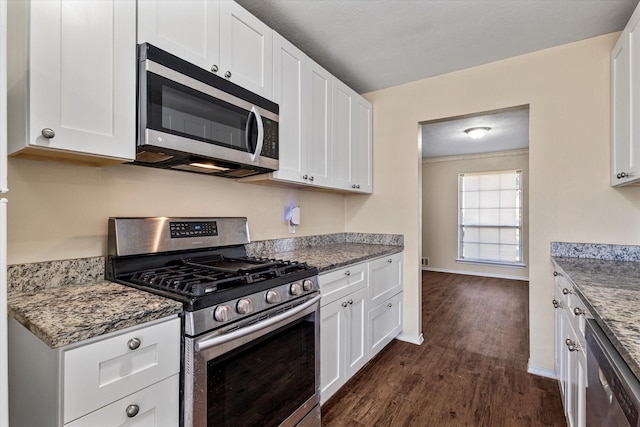 kitchen with dark hardwood / wood-style floors, dark stone countertops, white cabinetry, and stainless steel appliances