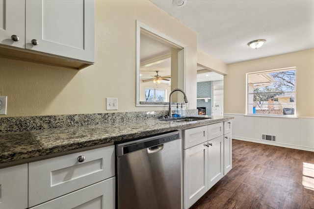 kitchen with ceiling fan, sink, stainless steel dishwasher, dark stone counters, and white cabinets