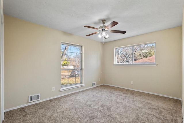 carpeted empty room featuring ceiling fan and a healthy amount of sunlight