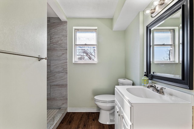 bathroom with tiled shower, plenty of natural light, hardwood / wood-style floors, and toilet