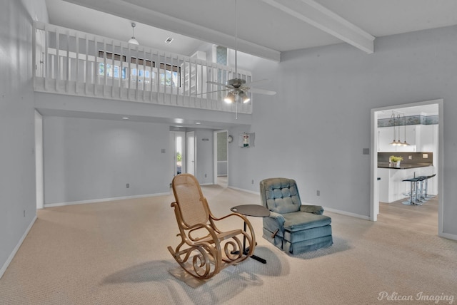 living area featuring a high ceiling, carpet floors, beam ceiling, and ceiling fan