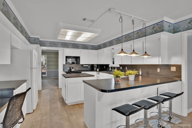 kitchen with a breakfast bar, white cabinets, light wood-type flooring, and backsplash