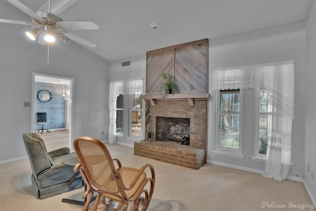 living room featuring a fireplace, vaulted ceiling, light carpet, ceiling fan, and a healthy amount of sunlight