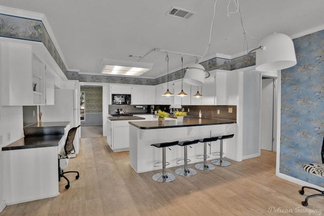 kitchen featuring white cabinets, light hardwood / wood-style floors, backsplash, and a breakfast bar area