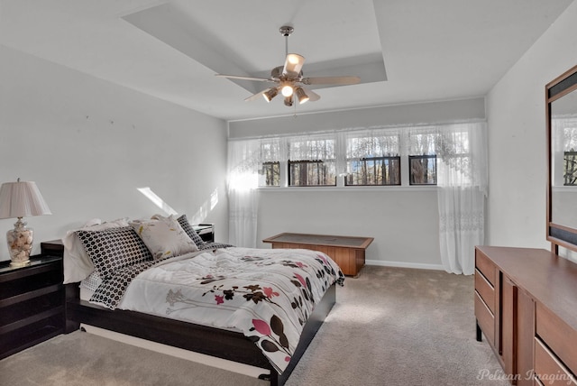 bedroom featuring ceiling fan, a raised ceiling, and light carpet