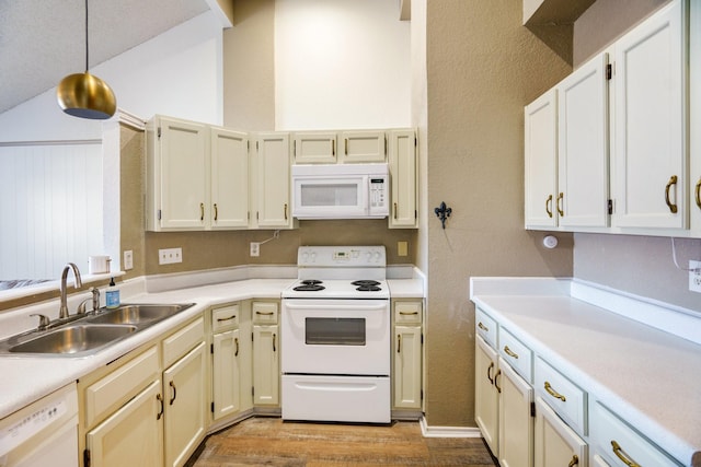 kitchen with sink, vaulted ceiling, white appliances, light wood-type flooring, and hanging light fixtures