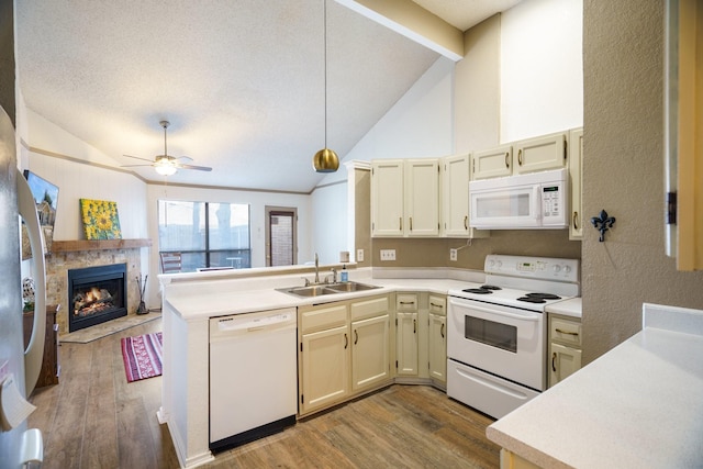 kitchen featuring white appliances, kitchen peninsula, a fireplace, sink, and lofted ceiling