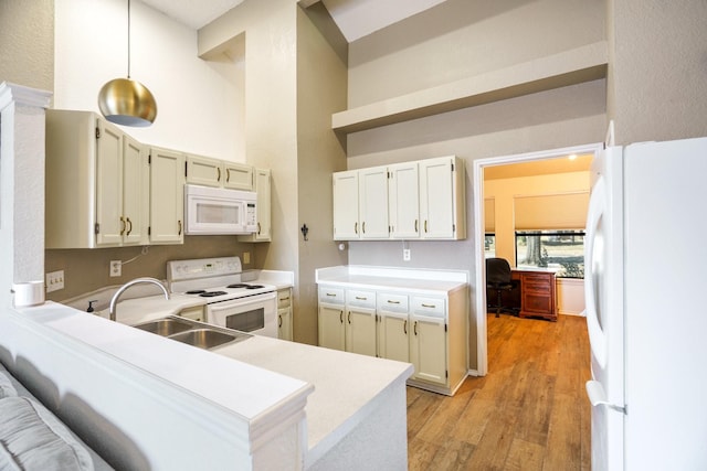 kitchen with sink, white appliances, light hardwood / wood-style floors, kitchen peninsula, and hanging light fixtures