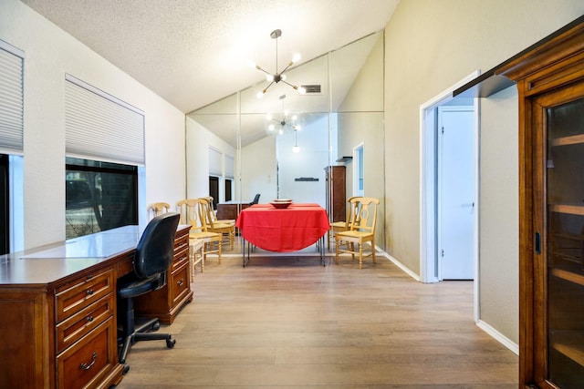 office with a notable chandelier, a textured ceiling, vaulted ceiling, and light hardwood / wood-style floors