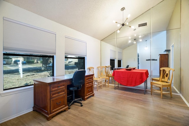 office space with light hardwood / wood-style floors, a healthy amount of sunlight, a notable chandelier, and lofted ceiling