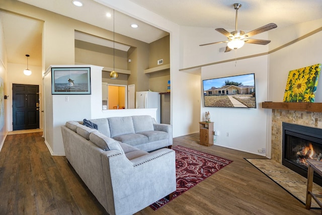 living room with a tiled fireplace, ceiling fan, high vaulted ceiling, dark hardwood / wood-style floors, and built in shelves