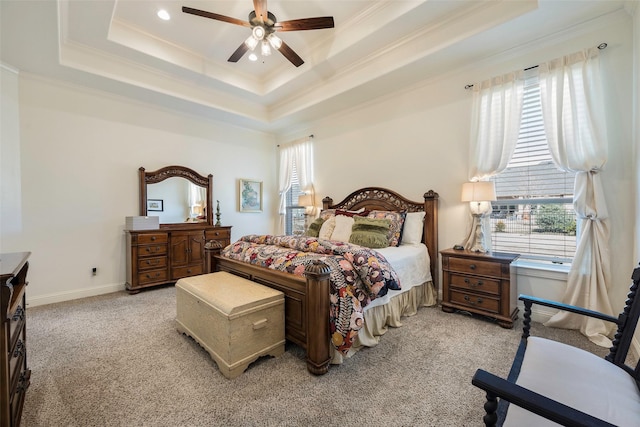 carpeted bedroom with a raised ceiling, multiple windows, and ceiling fan