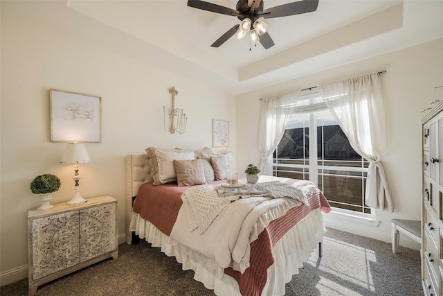 carpeted bedroom with ceiling fan and a raised ceiling