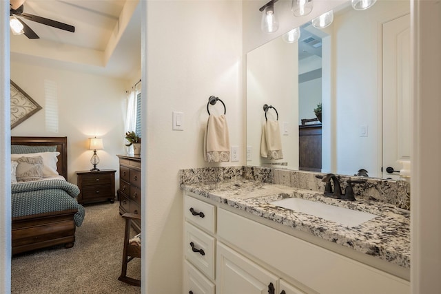 bathroom with a tray ceiling, ceiling fan, and vanity