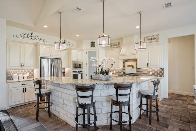 kitchen featuring pendant lighting, a breakfast bar, backsplash, appliances with stainless steel finishes, and a large island