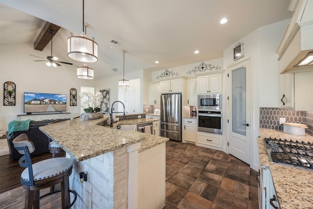 kitchen featuring backsplash, a large island with sink, hanging light fixtures, custom range hood, and stainless steel appliances