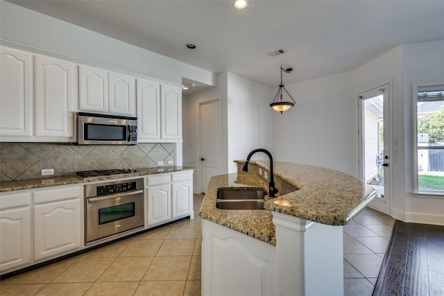 kitchen featuring white cabinets, hanging light fixtures, sink, an island with sink, and appliances with stainless steel finishes