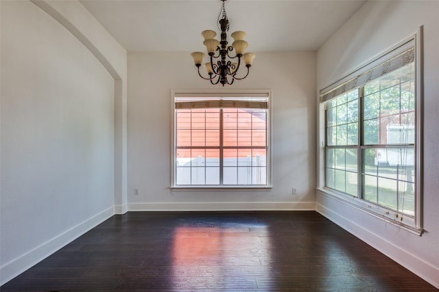 unfurnished room with an inviting chandelier and dark wood-type flooring