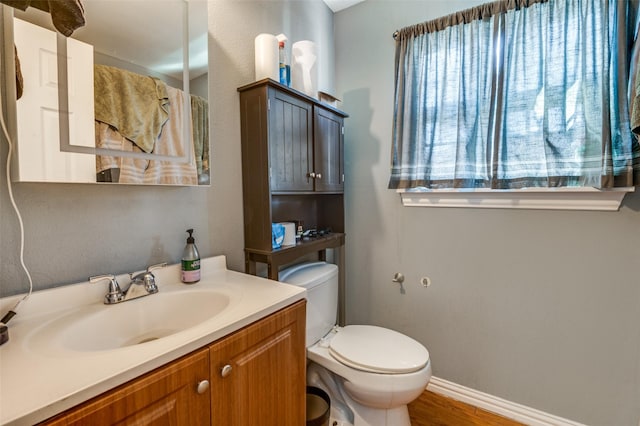 bathroom with wood-type flooring, vanity, and toilet