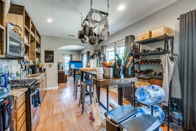 kitchen with a wealth of natural light, light hardwood / wood-style floors, light stone counters, and appliances with stainless steel finishes