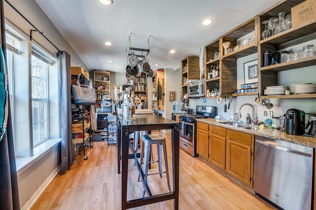 kitchen featuring sink, stainless steel appliances, light hardwood / wood-style floors, and light stone countertops