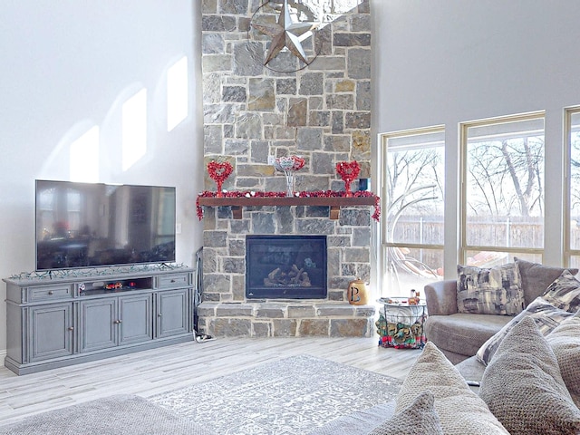 living room featuring light wood-type flooring and a stone fireplace