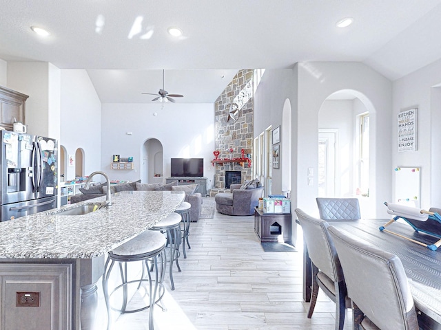 kitchen with a kitchen island with sink, light hardwood / wood-style floors, stainless steel fridge with ice dispenser, a fireplace, and sink